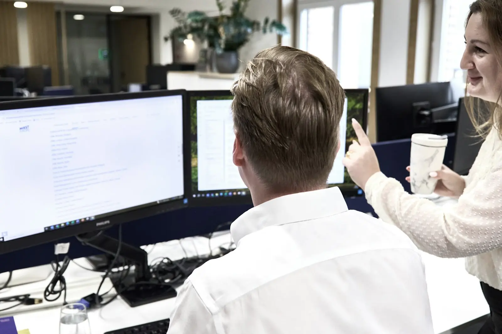Two people looking at data on screens in an office