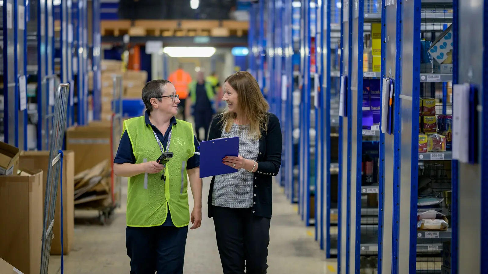 Deux employées qui discutent dans une allée d'entrepôt
