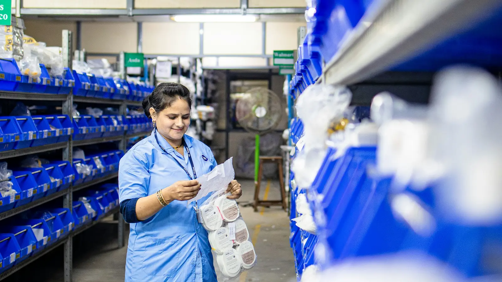 Une employée qui vérifie des pièces dans un rayonnage d'entrepôt