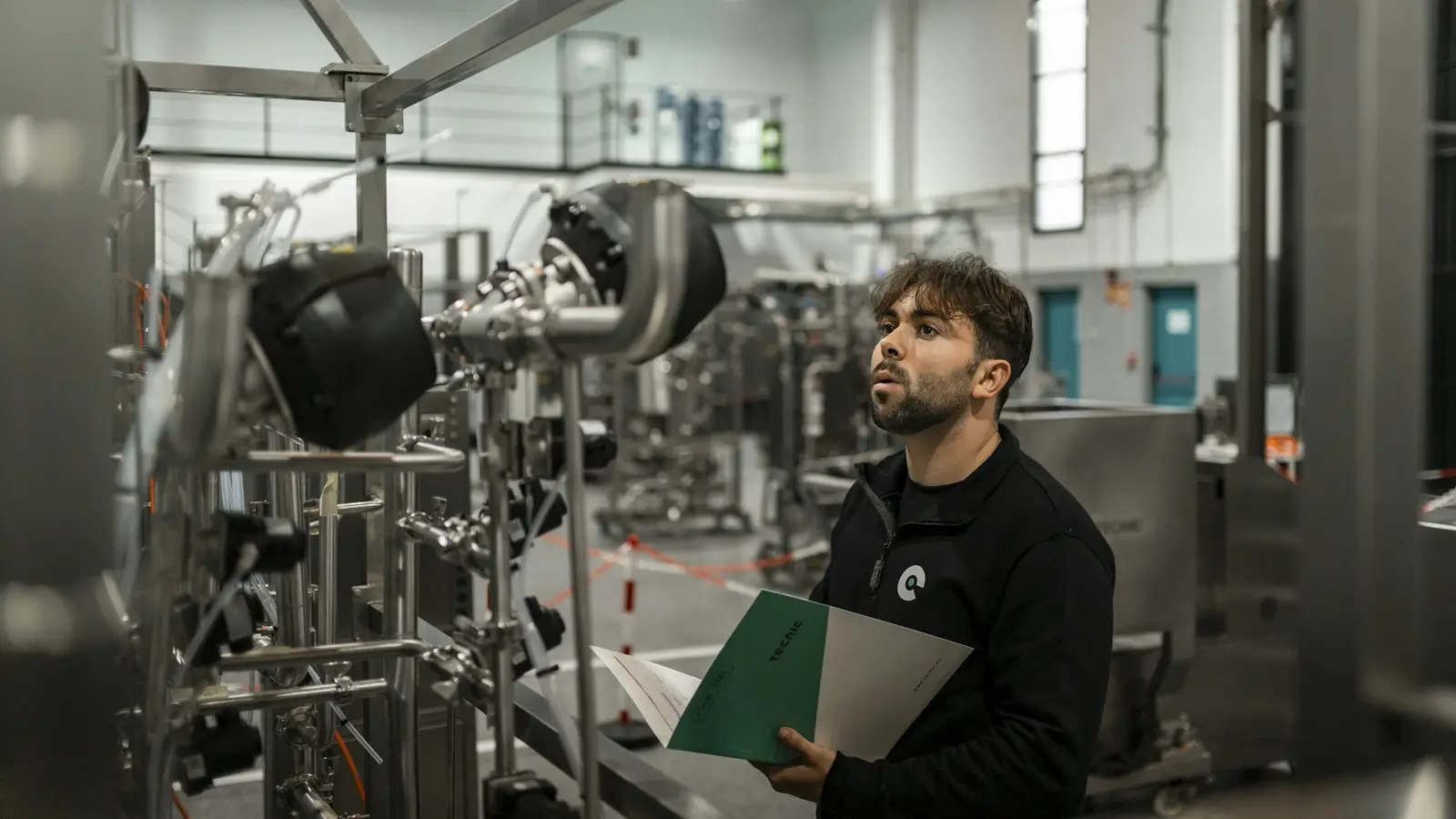 Un employé qui inspecte de la machinerie, dossier à la main