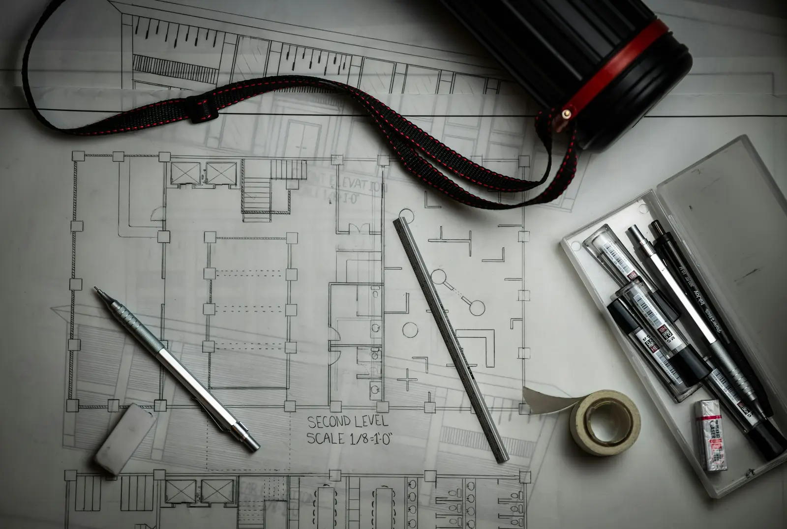 Des plans, des crayons et une règle métallique vus du dessus sur une table de travail