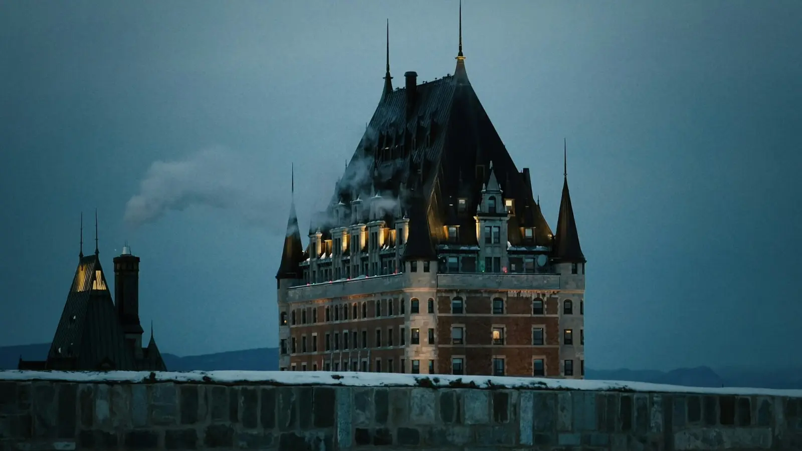 Le Château Frontenac au crépuscule, derrière les remparts enneigés de Québec