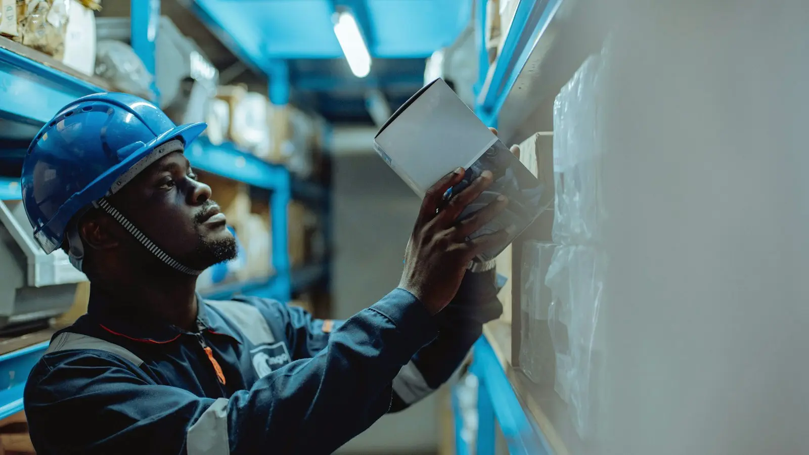 A foreman in a hard hat reads a route sheet on the plant floor.